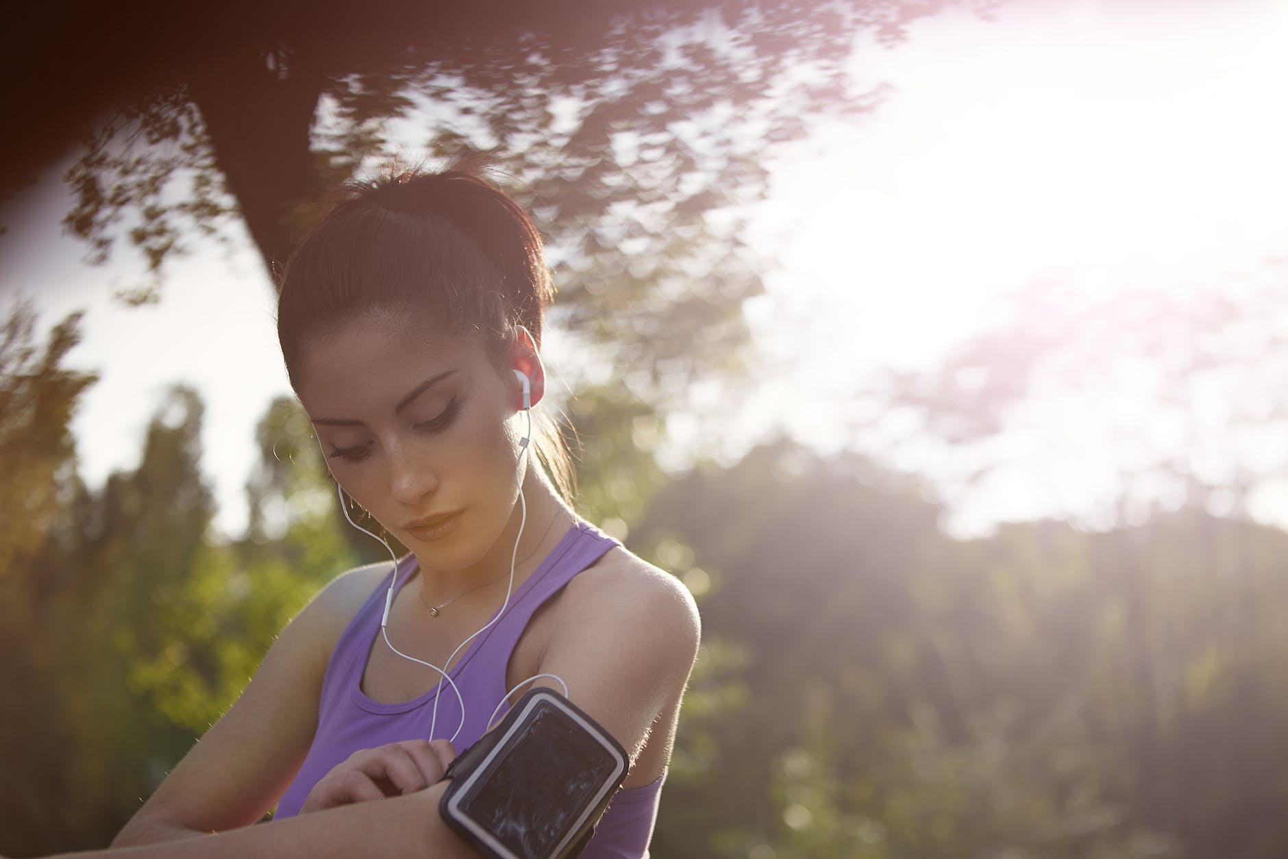 young sportswoman listening to music in park
